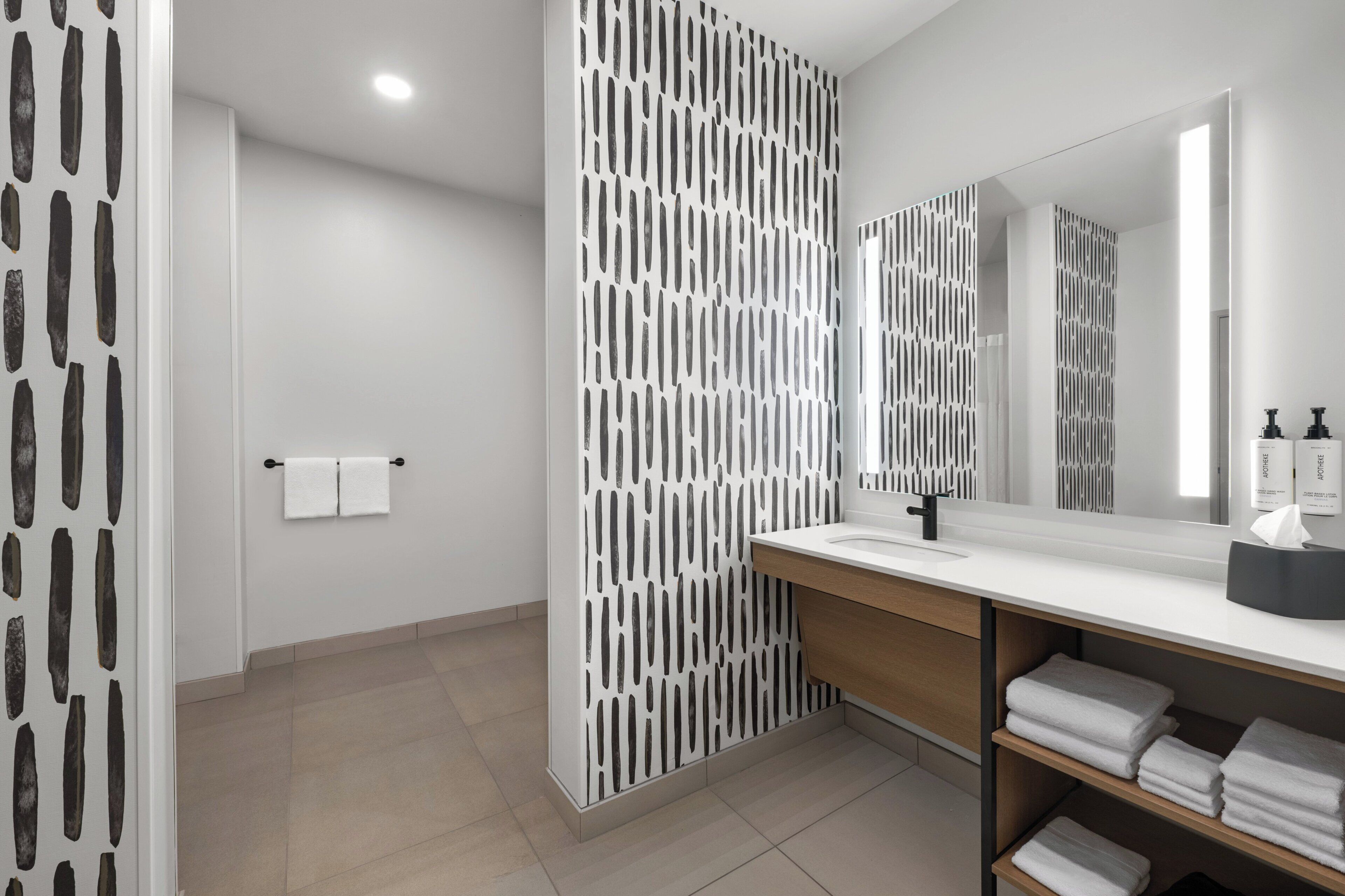 A modern bathroom with a white sink, a mirror, and a towel rack.
