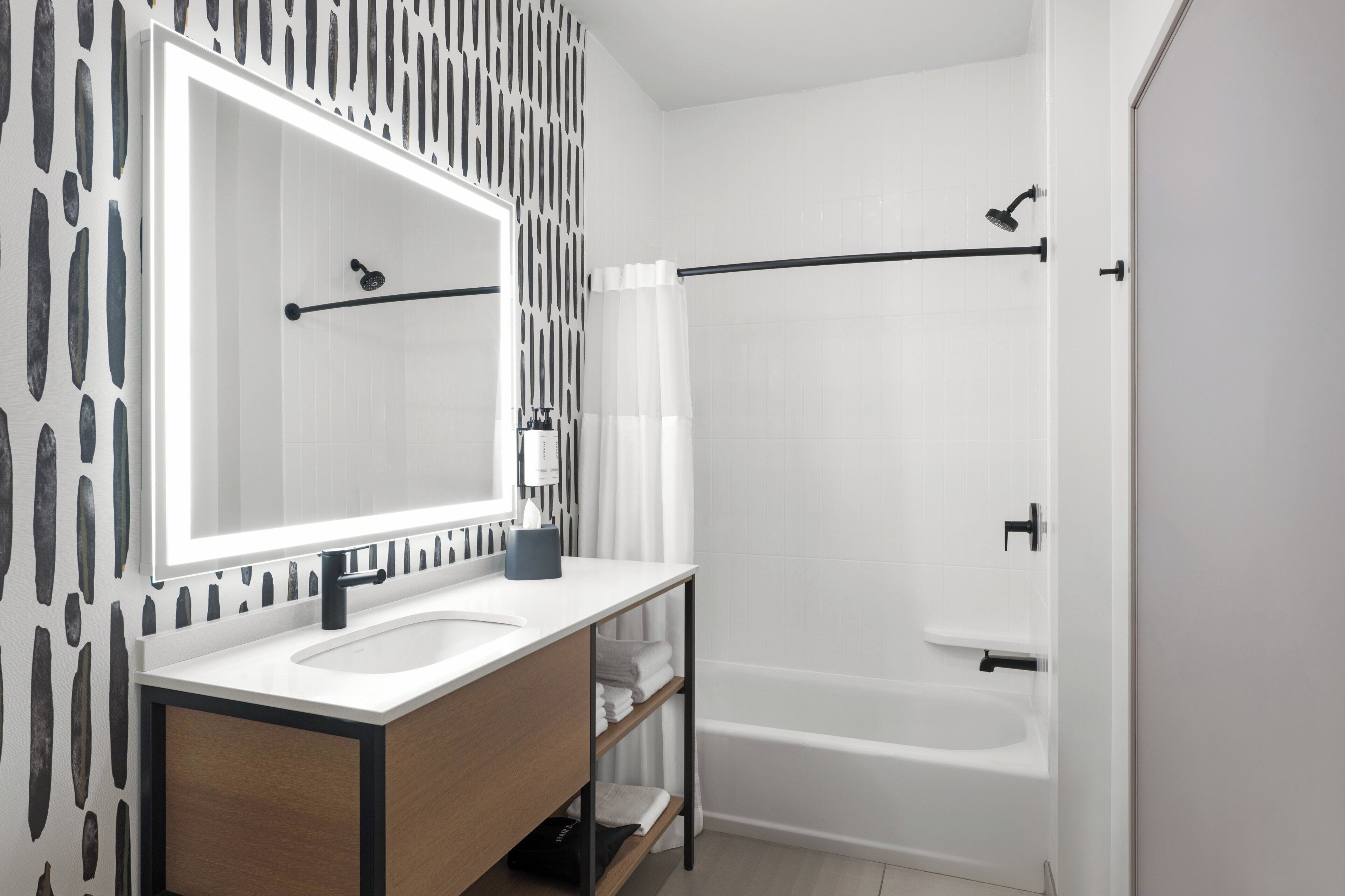 A modern bathroom with a large mirror, a sink, a bathtub, and a shower.