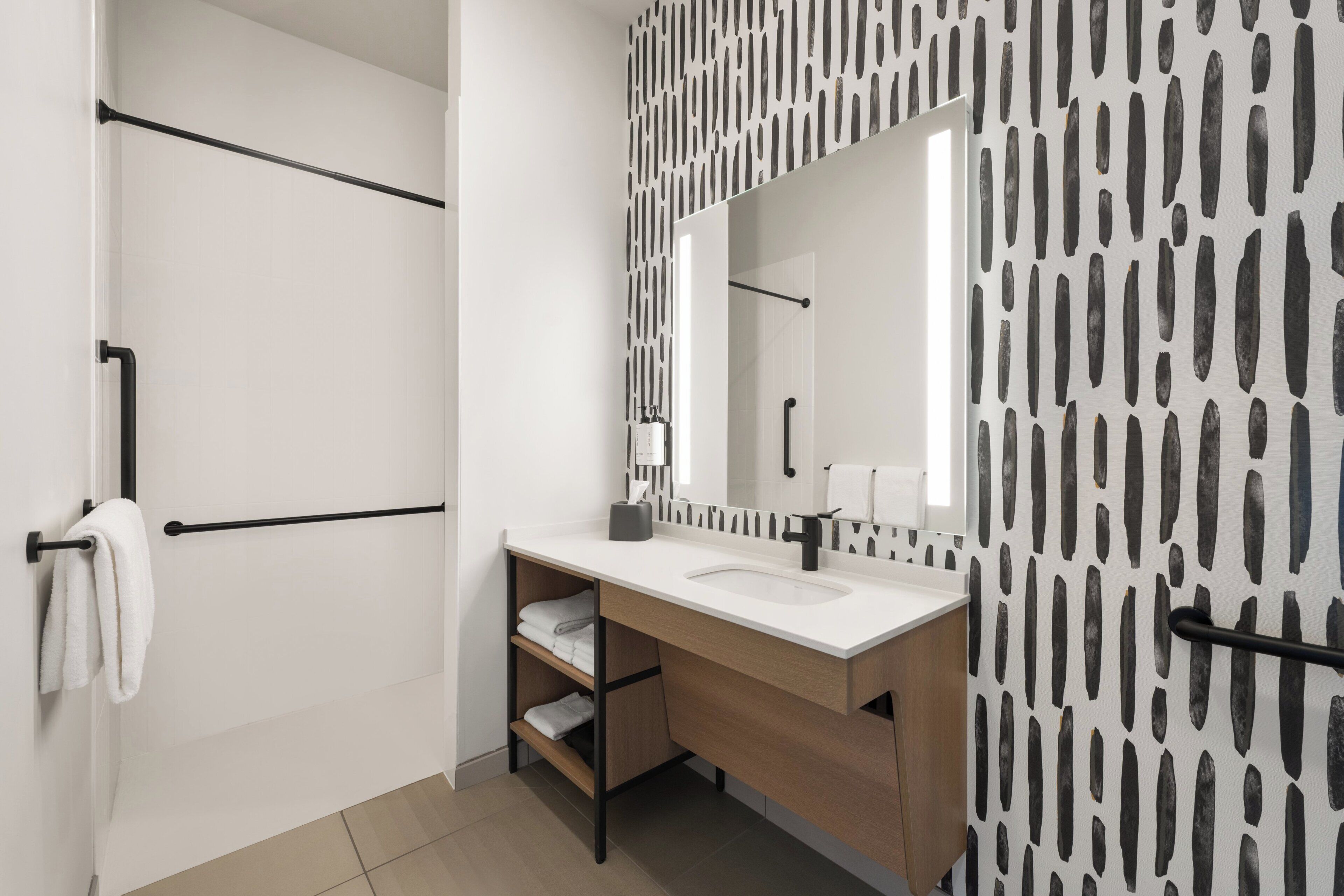 A modern bathroom with a white sink, black towel rack, and a patterned wall.