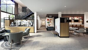 A modern hotel lobby with a central staircase, seating areas, a reception desk, and a bar. - Atwell Suites Belgrade Bozeman Airport by IHG (Belgrade)