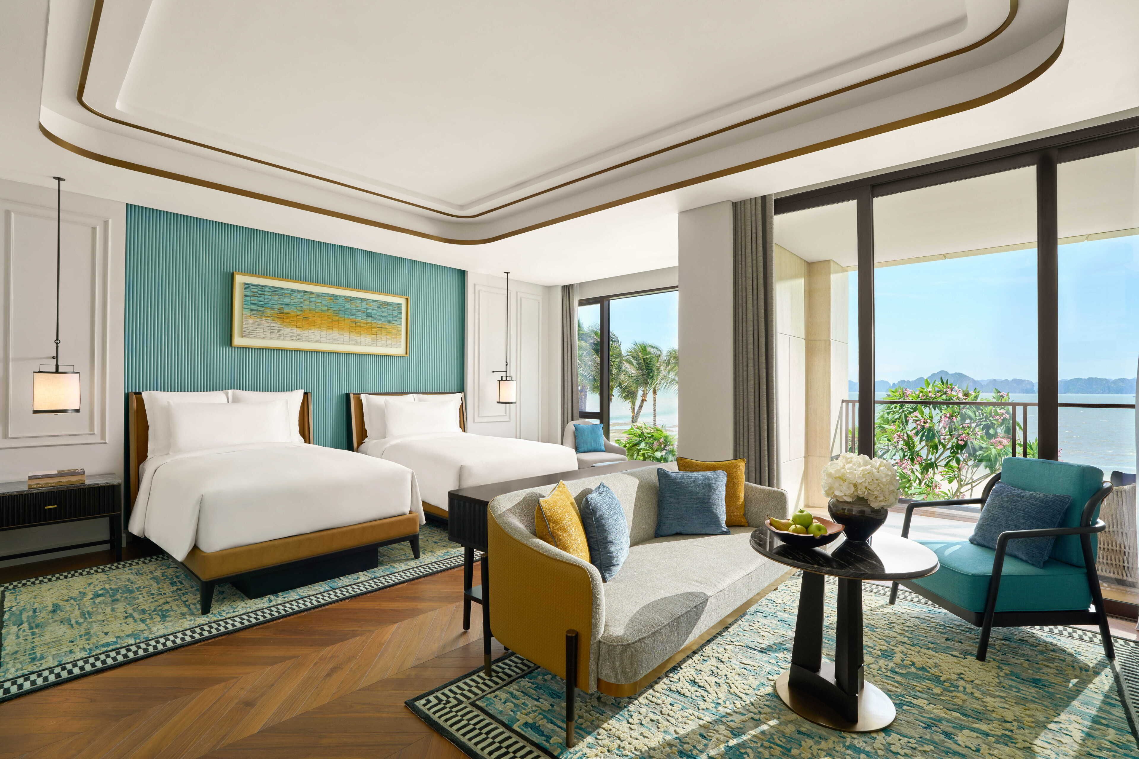 A hotel room with two beds, a sofa, a balcony with a view, and a large window.