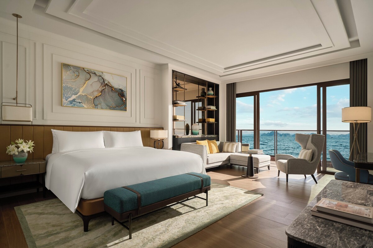 Une chambre d’hôtel moderne dotée d’un grand lit, d’un coin salon et offrant une vue sur la mer.