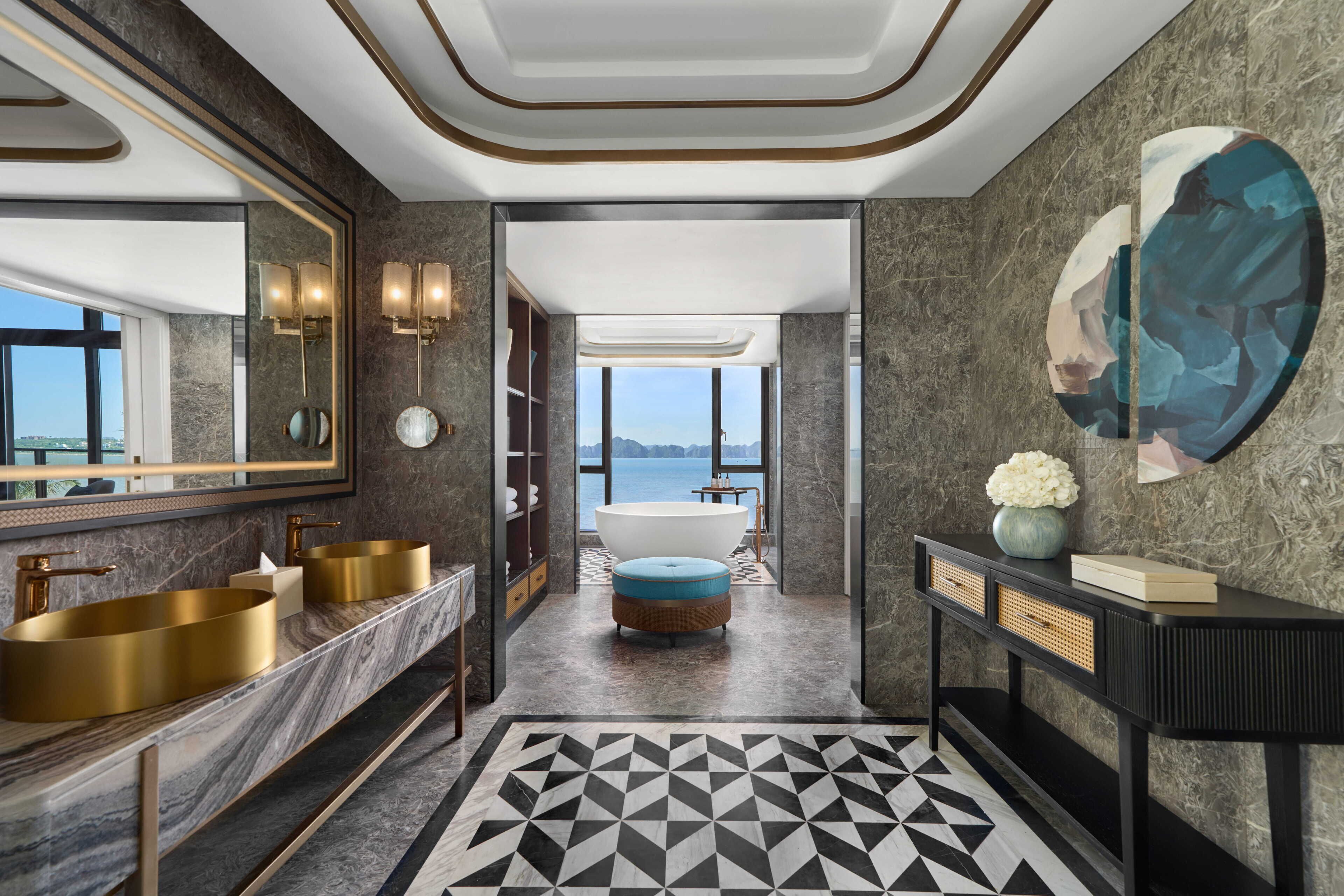 A modern bathroom with dual sinks, a bathtub, and a large window offering a view of the sea.