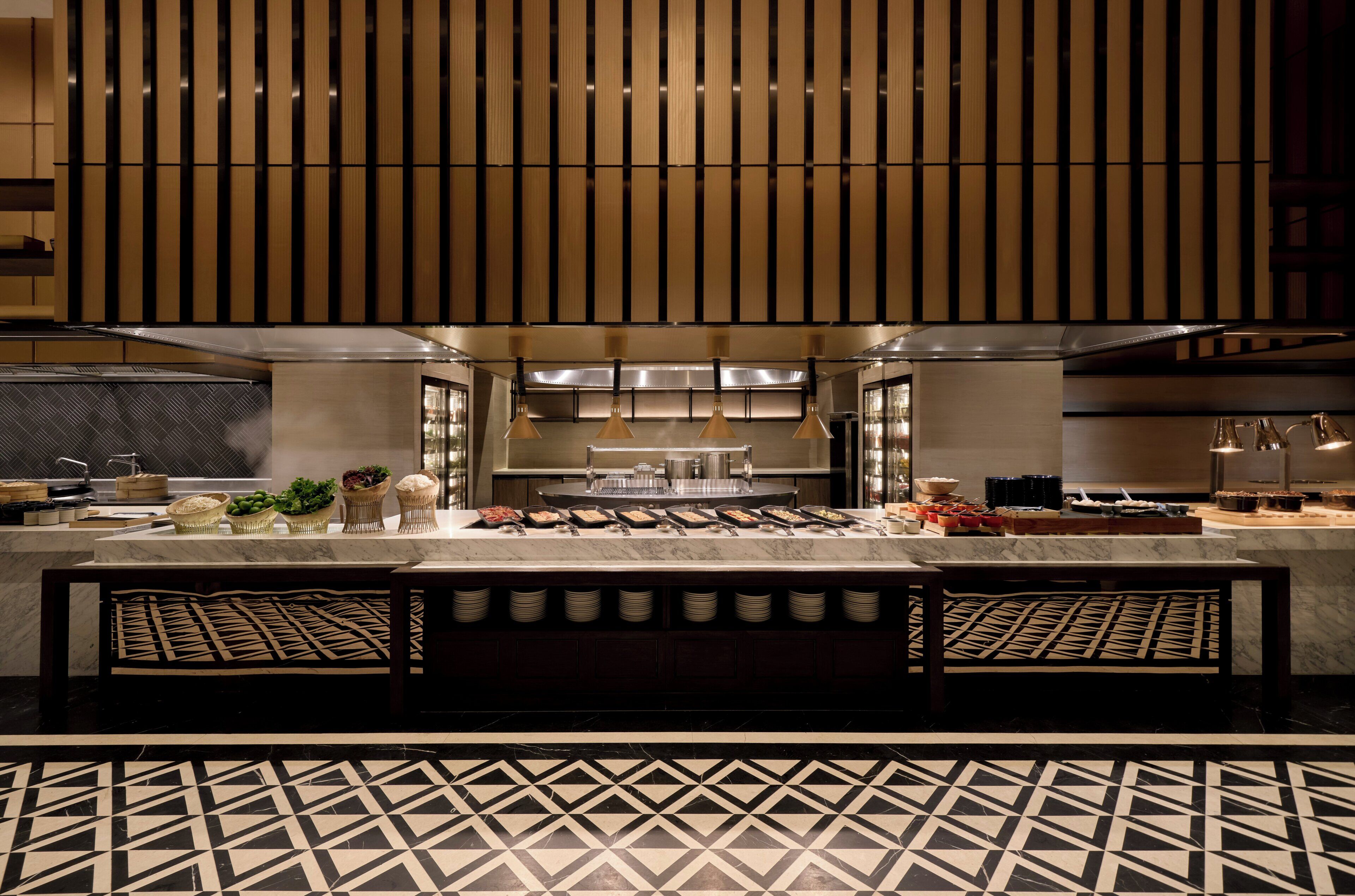 A modern kitchen with a marble countertop, hanging lights, and a patterned floor.