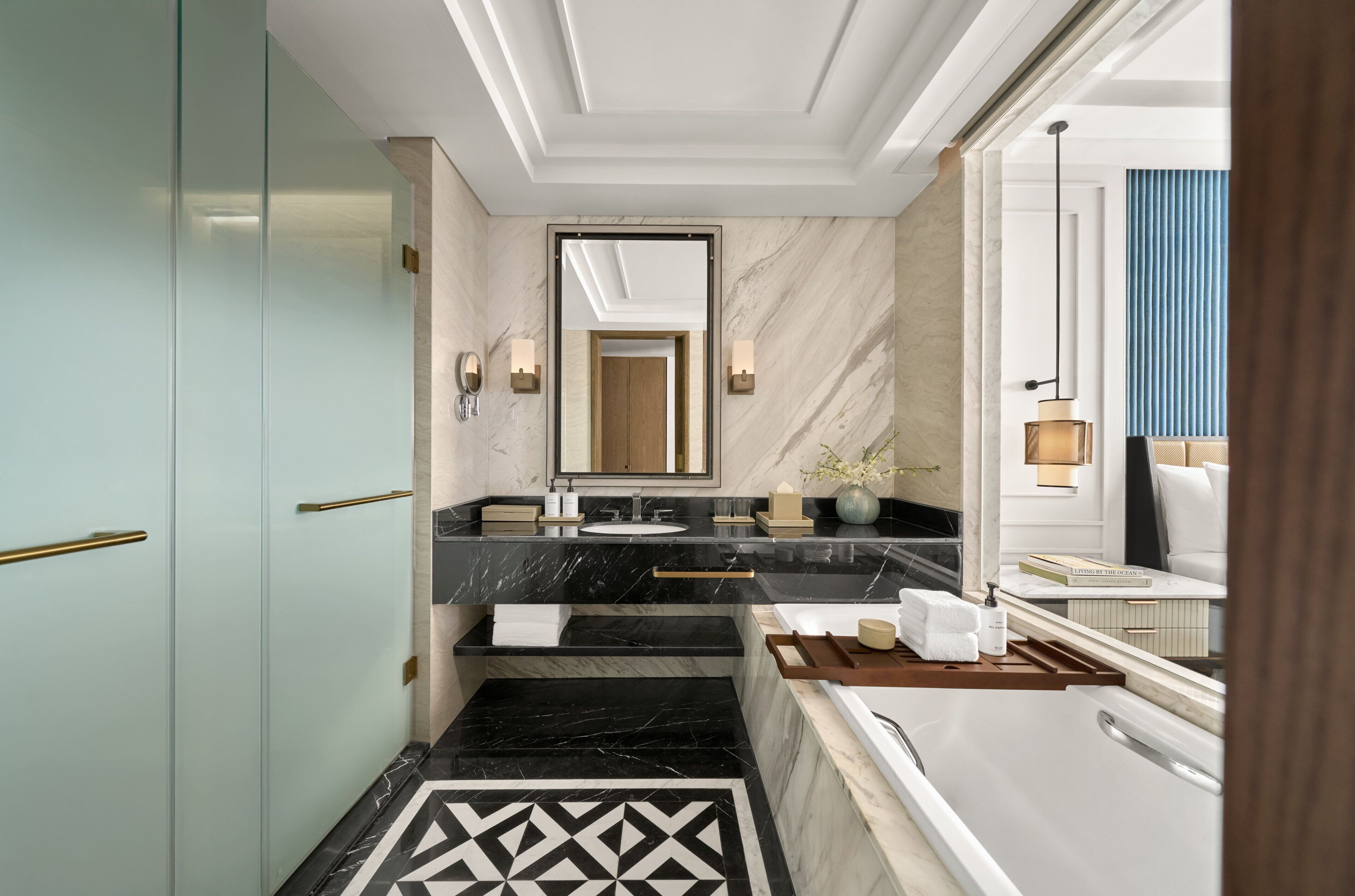 A modern bathroom with a marble vanity, dual sinks, a large mirror, and a bathtub.