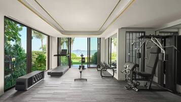 A modern gym with large windows, exercise equipment, and a bench.