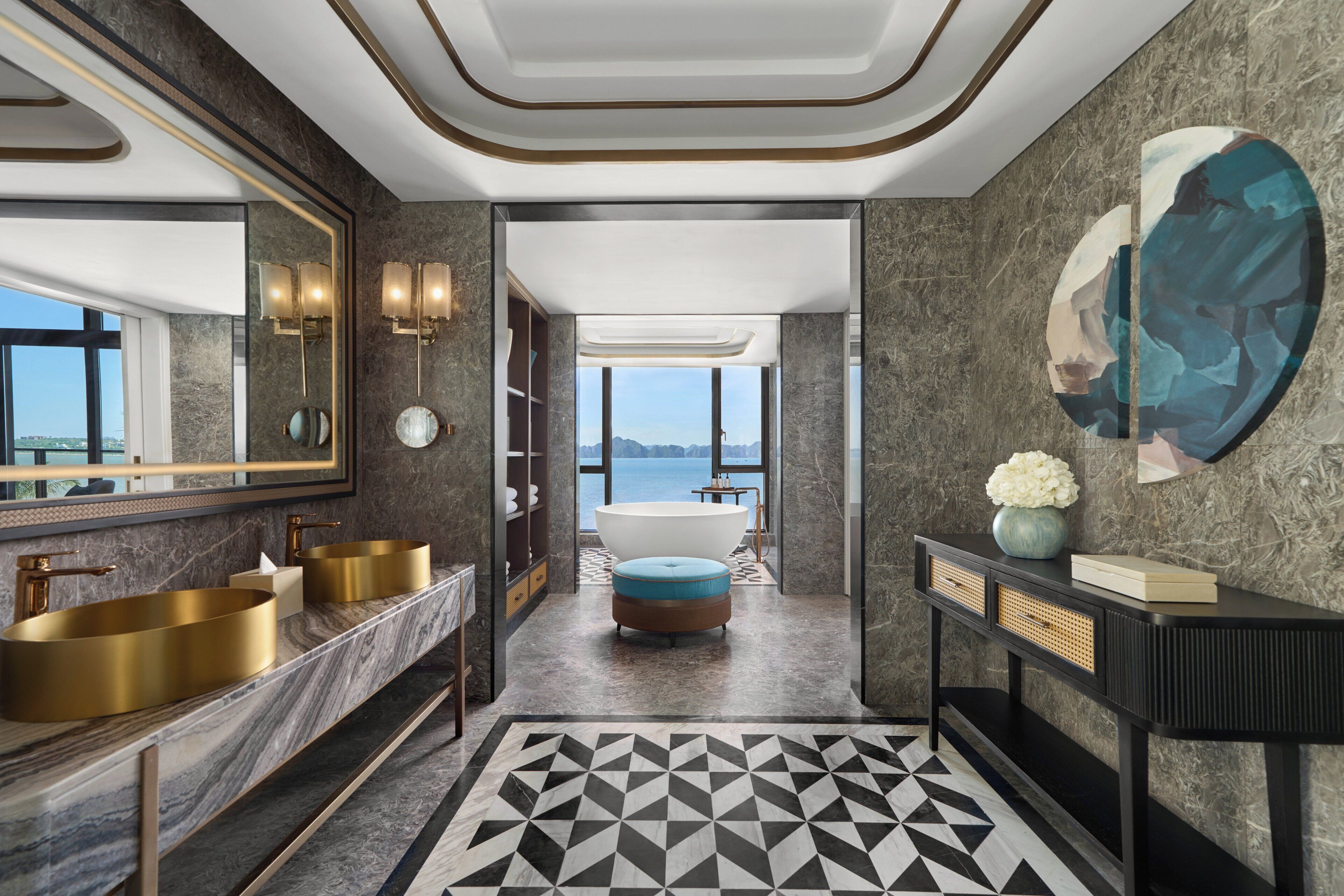 A modern bathroom with dual sinks, a bathtub, and a large window offering a view of the sea.