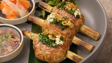A plate with grilled meat skewers, a bowl of soup, and a glass of wine on a table.