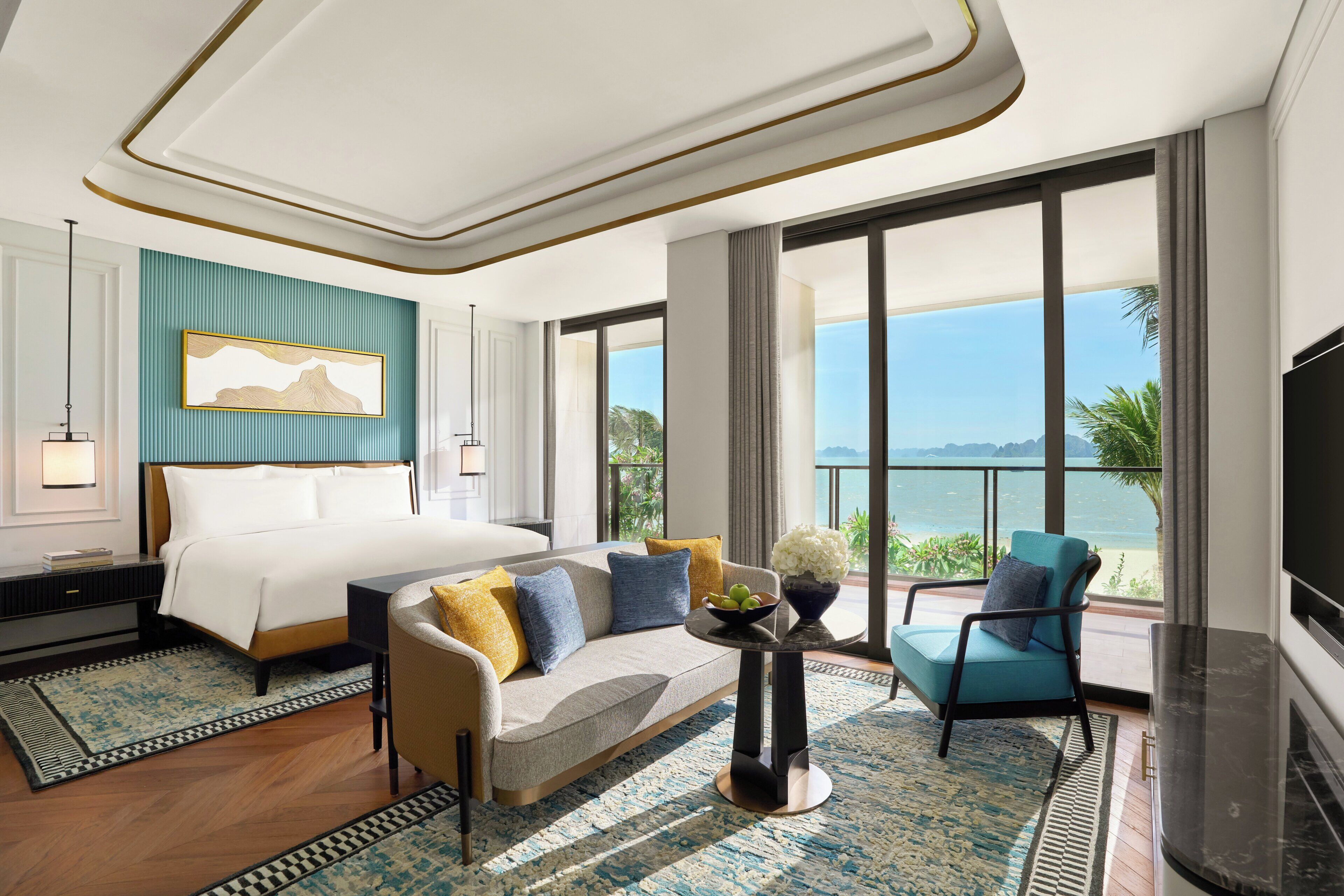 Habitación de hotel con cama, sofá, televisión y un ventanal con vistas.