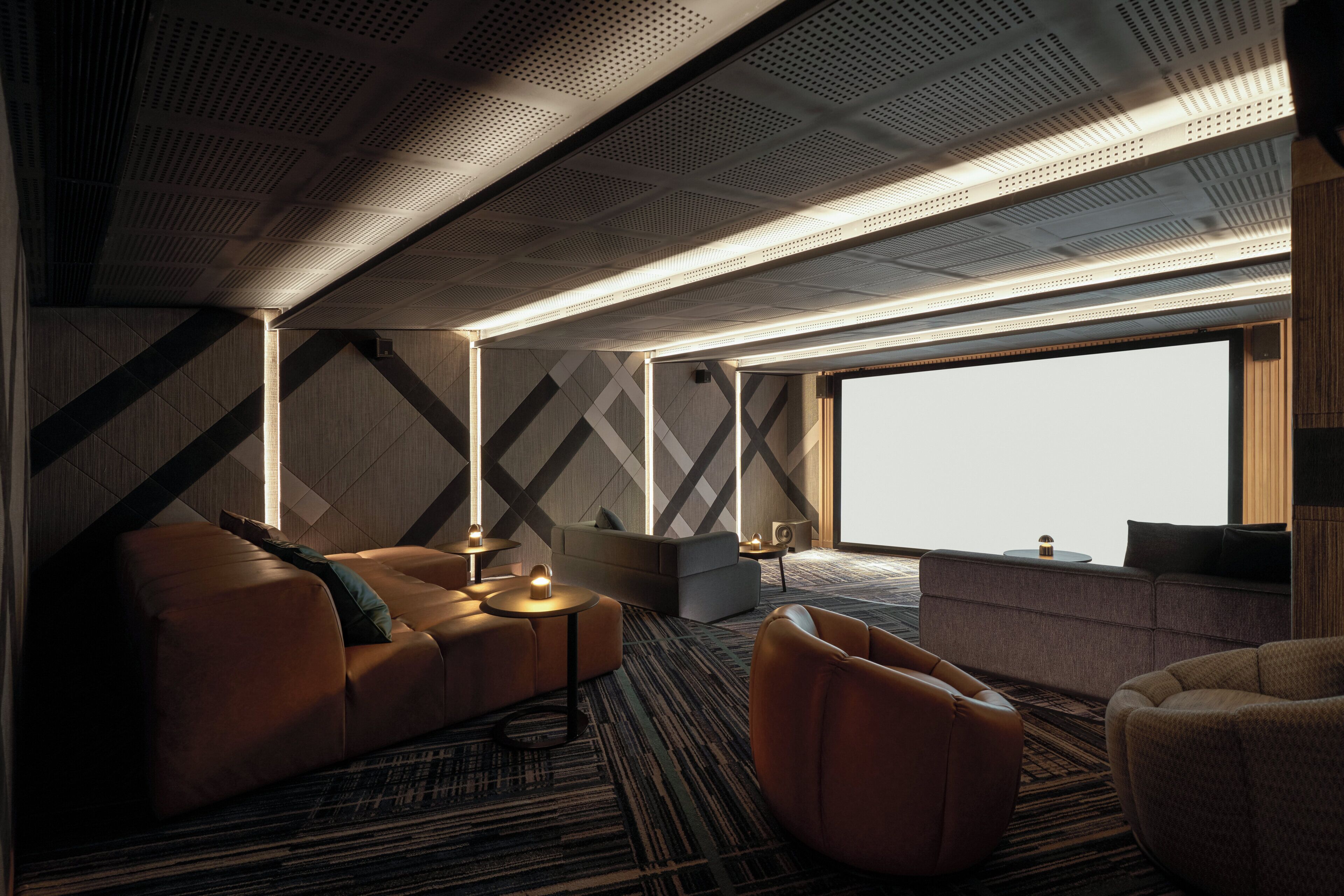 Una habitación de hotel moderna con un ventanal grande, un sofá, una silla y una mesita.