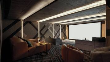 Una habitación de hotel moderna con un ventanal grande, un sofá, una silla y una mesita.