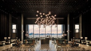 Un hall d’entrée spacieux, agrémenté d’un grand lustre, d’un coin salon et offrant une vue sur les montagnes grâce à de grandes fenêtres.