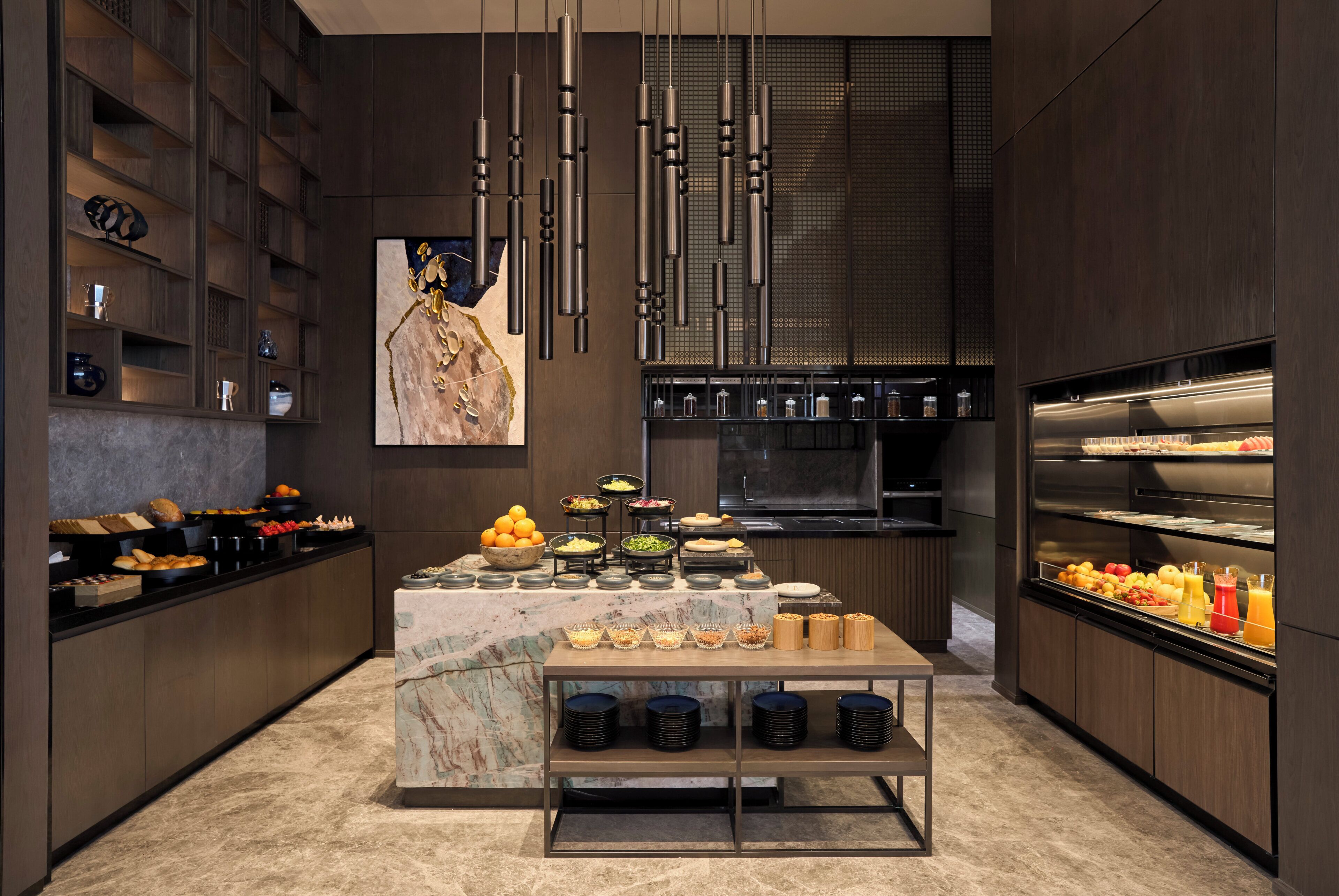 A modern kitchen with a marble countertop, a buffet setup, and a stainless steel refrigerator.