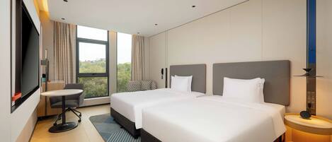 A modern hotel room with two beds, a desk, a chair, a TV, and a large window with a view.
