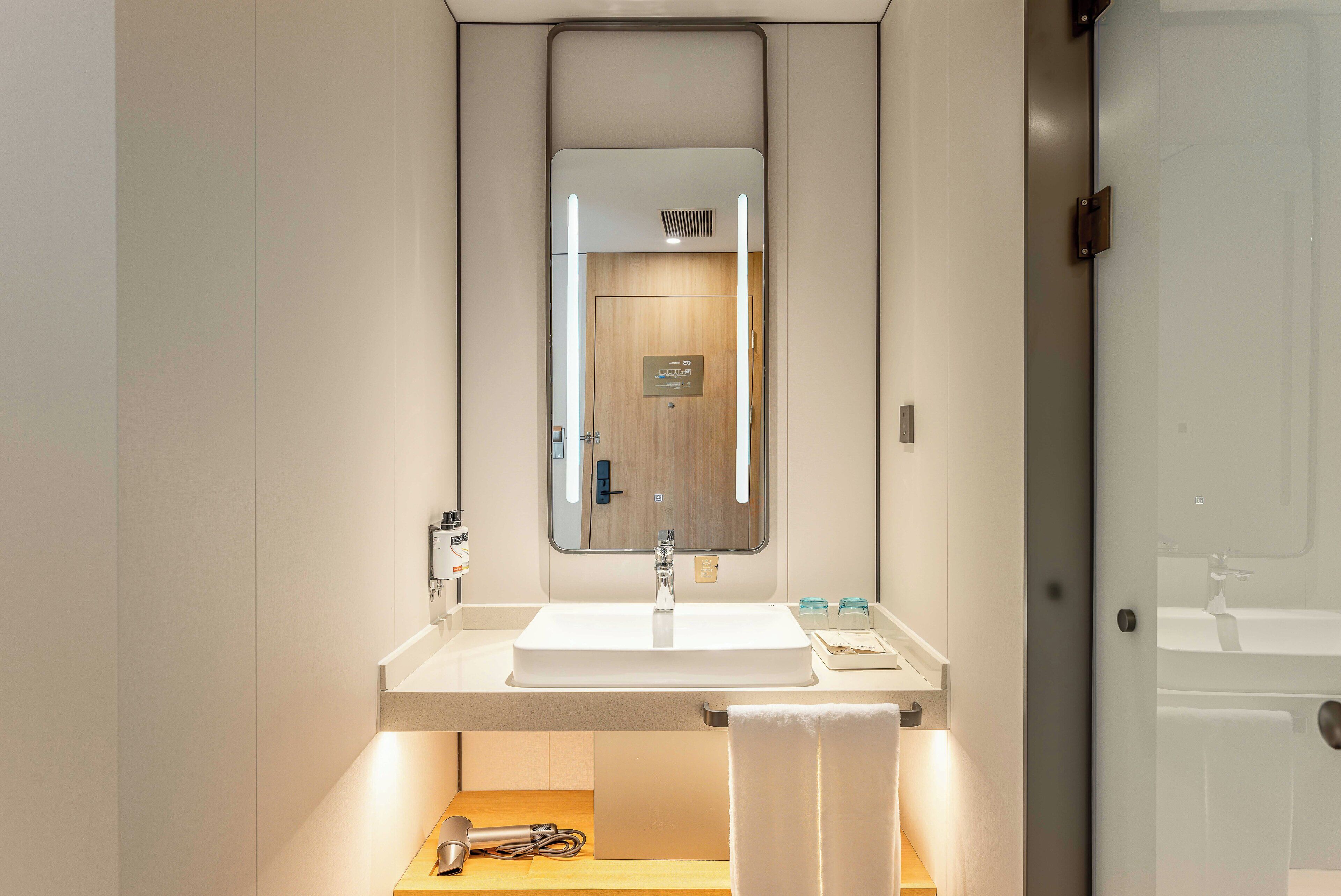 Ein modernes Badezimmer mit Waschbecken, Spiegel und Handtuchhalter.