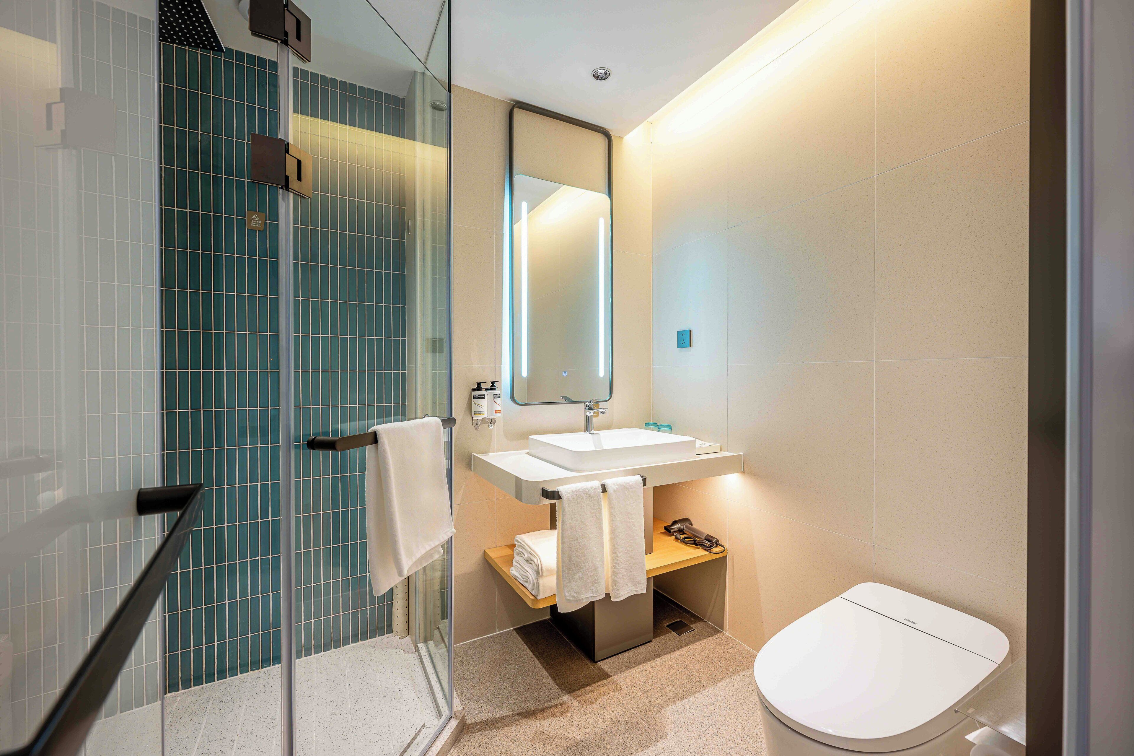 A modern bathroom with a glass shower enclosure, a white sink, and a toilet.