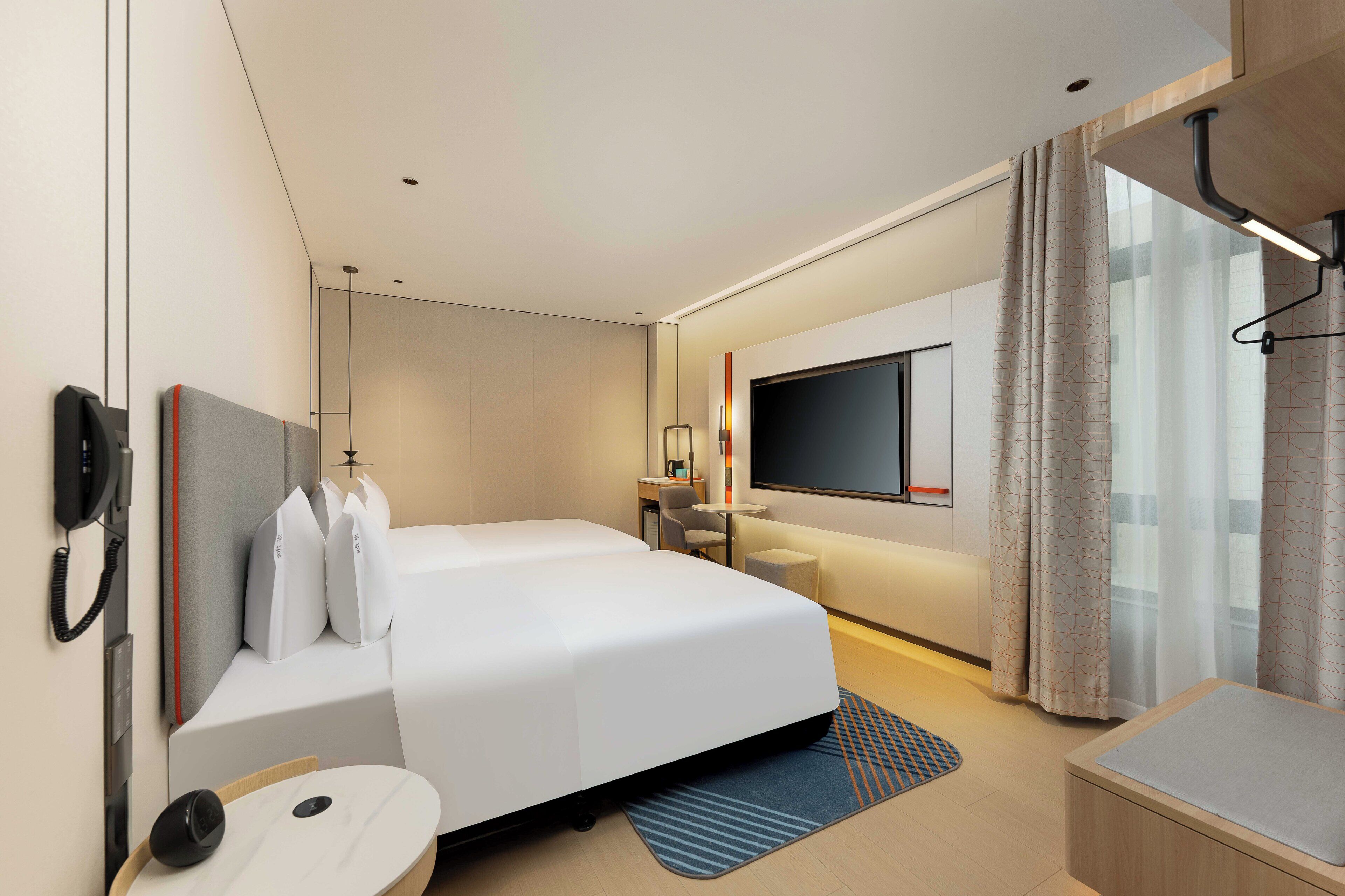 Une chambre d’hôtel moderne équipée d’un grand lit, d’un bureau, d’une télévision à écran plat et d’une salle de bain.