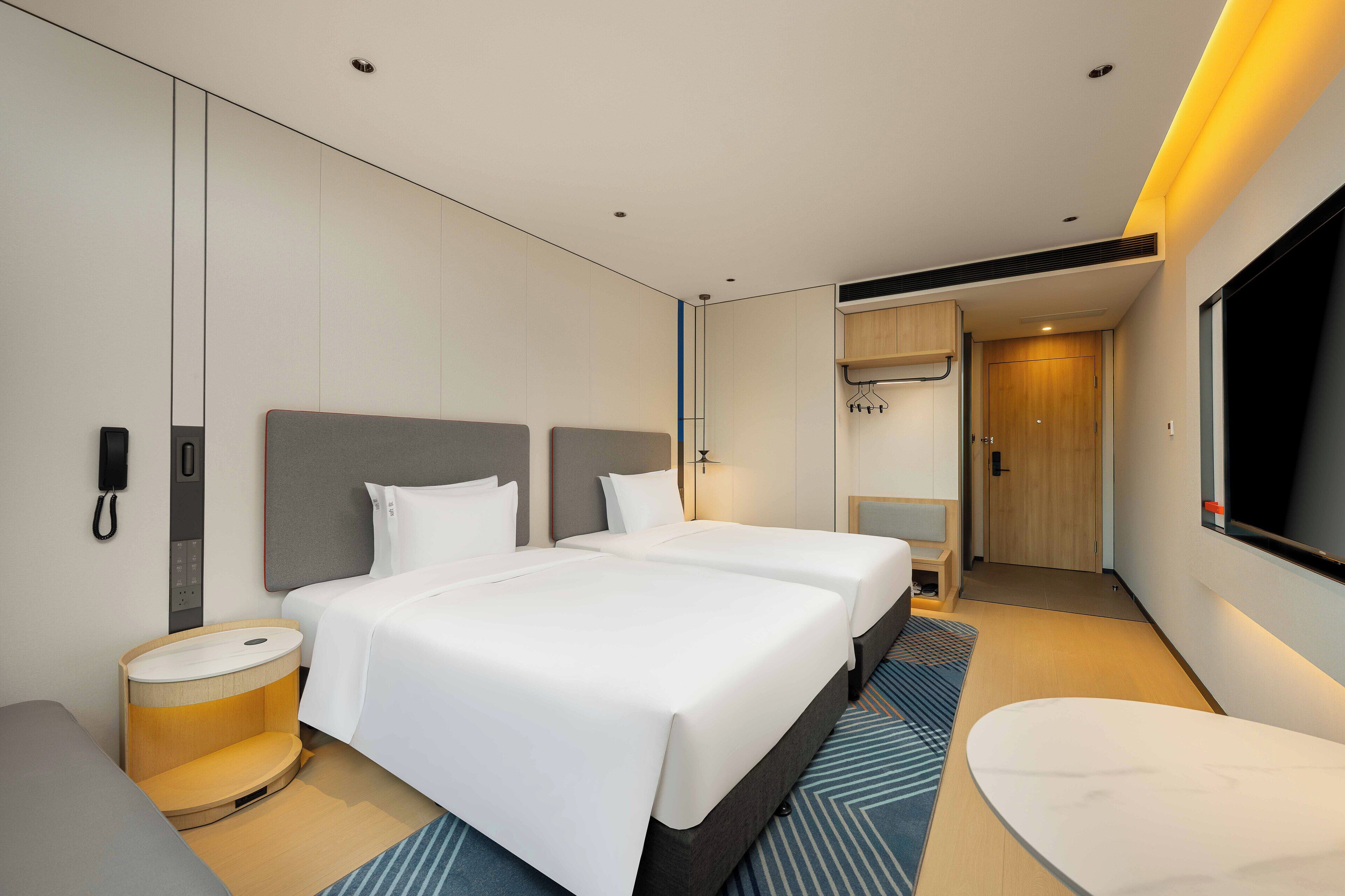 Habitación de hotel moderna con dos camas, un escritorio, una silla y un televisor.