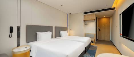 Une chambre d’hôtel moderne équipée de deux lits, d’un bureau, d’une chaise et d’un téléviseur.