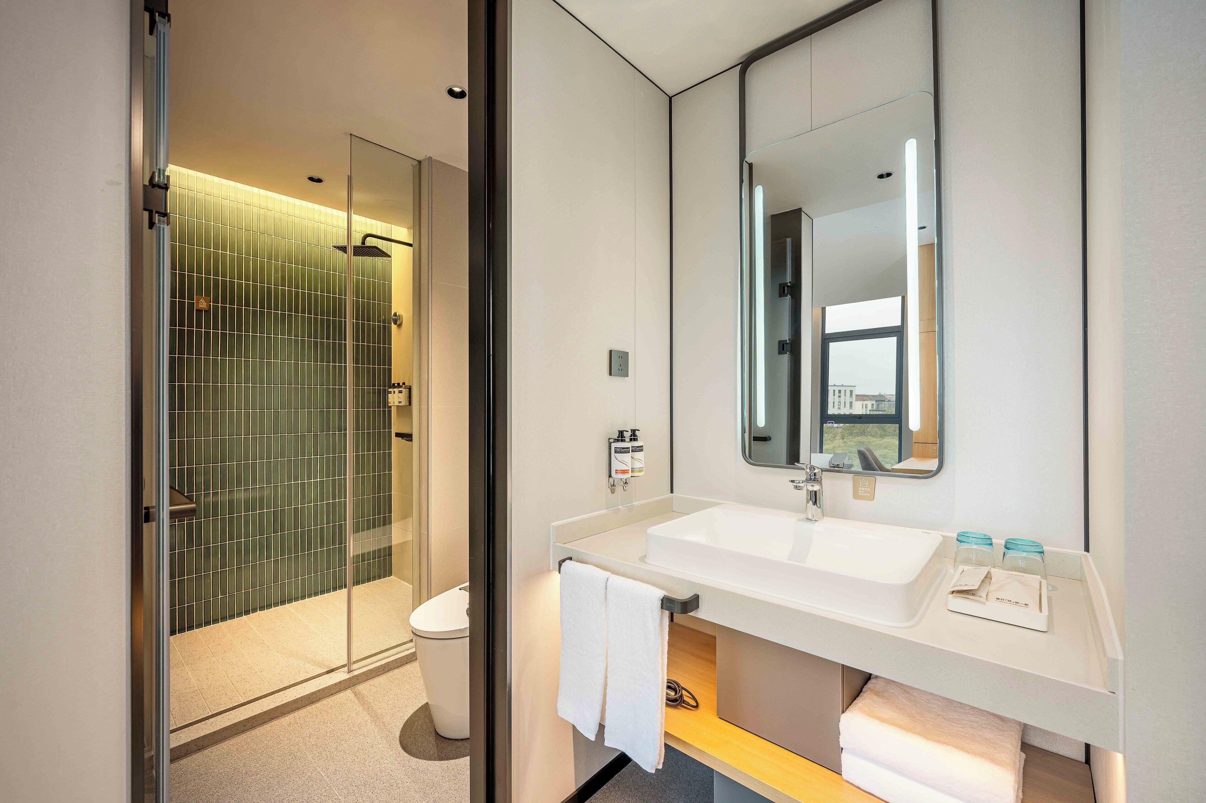 A modern bathroom with a glass shower enclosure, a white sink, and a large mirror.