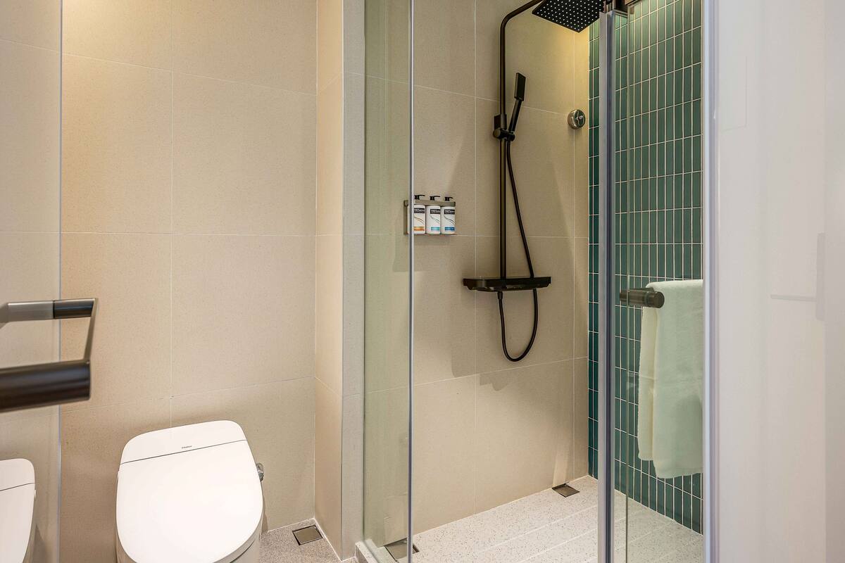 Un baño moderno con ducha de vidrio, inodoro y toallero.