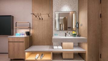 A modern bathroom with a wooden vanity, a mirror, and a built-in shoe storage.