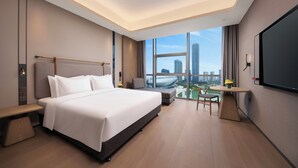 A modern hotel room with a large bed, a desk, a small table, and a large window offering a city view. - Holiday Inn Express Suzhou North Station by IHG (Suzhou)