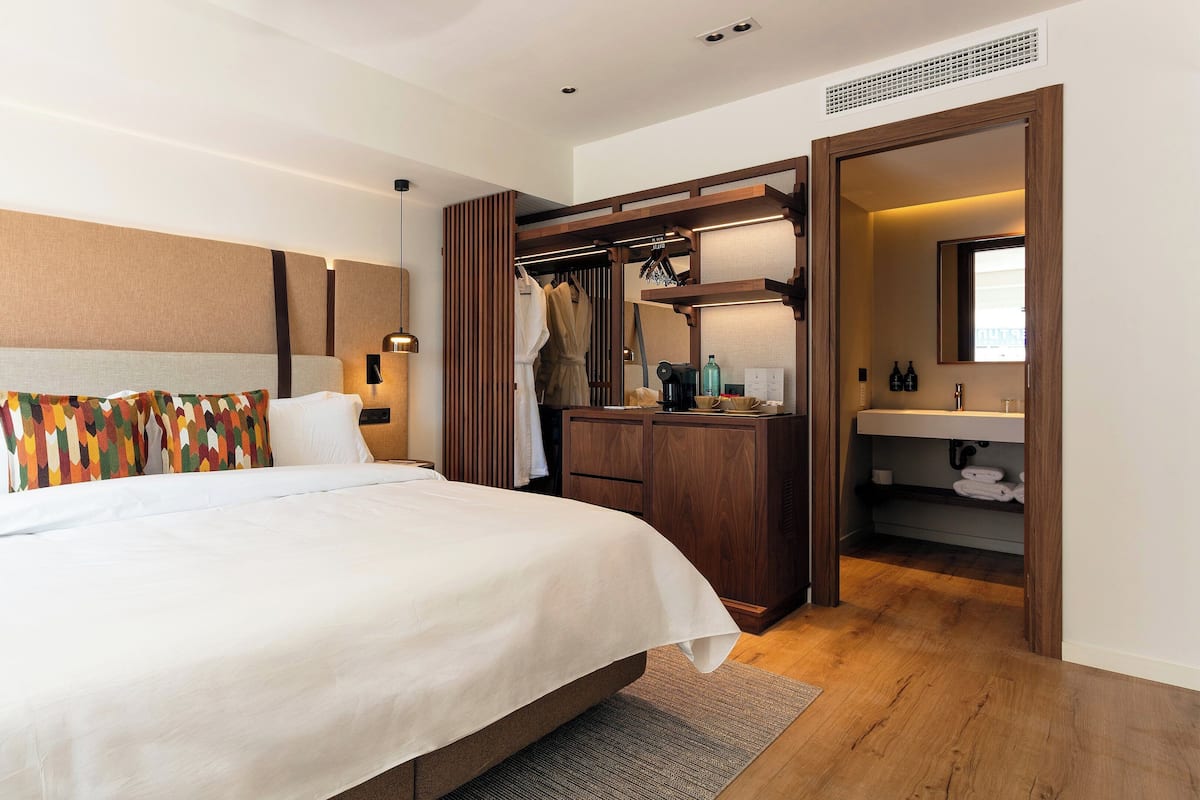 Habitación de hotel con cama, mesita de noche, armario y baño.