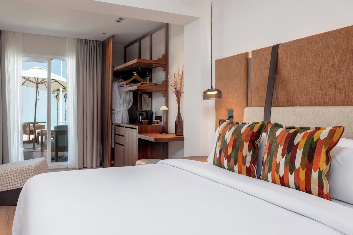 Una habitación de hotel moderna con una cama grande, un escritorio, una silla y un balcón con vistas.
