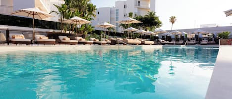 Una piscina al aire libre, sombrillas, sillones reclinables de piscina