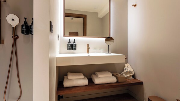 A bathroom with a white sink, a mirror, a towel rack, and a showerhead. - Hotel Indigo Gandia Beach by IHG (Gandia)