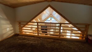 A room with a sloped ceiling, wooden beams, and a view through a window with a wooden frame. - Cabin #5 at Hyatt Lake Resort (Jackson County)