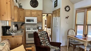 A cozy kitchen with wooden cabinets, a microwave, stove, and a dining area with a table and chairs. - Cabin #2 at Hyatt Lake Resort (Jackson County)