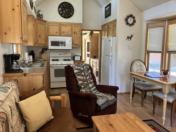 A cozy kitchen with wooden cabinets, a microwave, stove, and a dining area with a table and chairs.