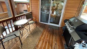 A wooden deck with a table and chairs, a sliding glass door, and a barbecue grill. - Cabin #2 at Hyatt Lake Resort (Jackson County)