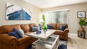 A living room with two brown leather sofas, a wooden coffee table, and a large abstract painting on the wall.