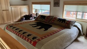 Une chambre avec un grand lit, une tête de lit en bois et une fenêtre avec des stores.