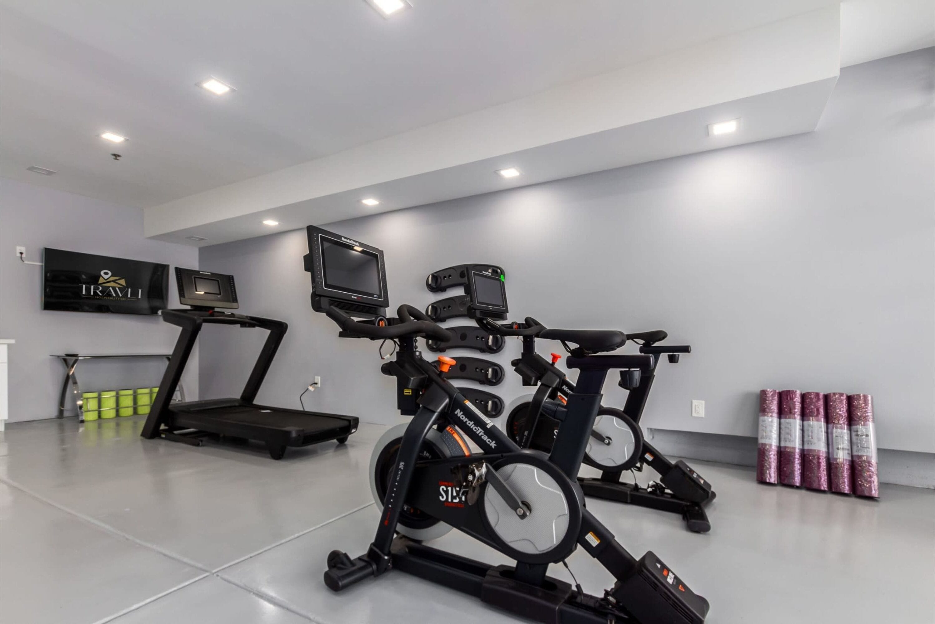 A gym with treadmills, stationary bikes, and a rowing machine.