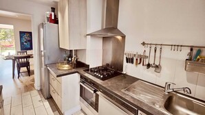 Una cocina moderna con estufa a gas, pileta de acero inoxidable y utensilios colgantes.