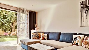 Una sala de estar moderna con un sofá seccional, una mesita de centro y vistas a un jardín a través de amplios ventanales.