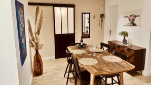 Un comedor con una mesa de madera, sillas y elementos decorativos como un jarrón con plumas de pájaro y un adorno colgante.