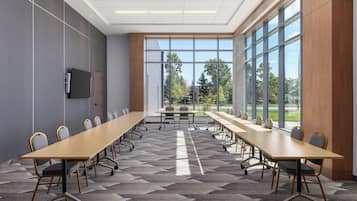 A conference room with a long table, chairs, and a large window with a view of trees and buildings.