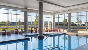 A modern indoor pool area with clear views of the outside, large windows, and seating around the pool. - Staybridge Suites Montréal Airport - St-Laurent by IHG (Montreal)