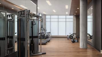 A spacious gym with cardio machines, weightlifting equipment, and a wooden floor.