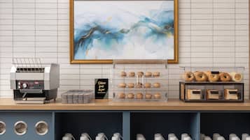 A bakery display with pastries, a coffee machine, and a framed abstract painting on the wall.