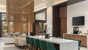 A modern dining area with a long table, green chairs, and a white vase with flowers. - Staybridge Suites Montréal Airport - St-Laurent by IHG (Montreal)