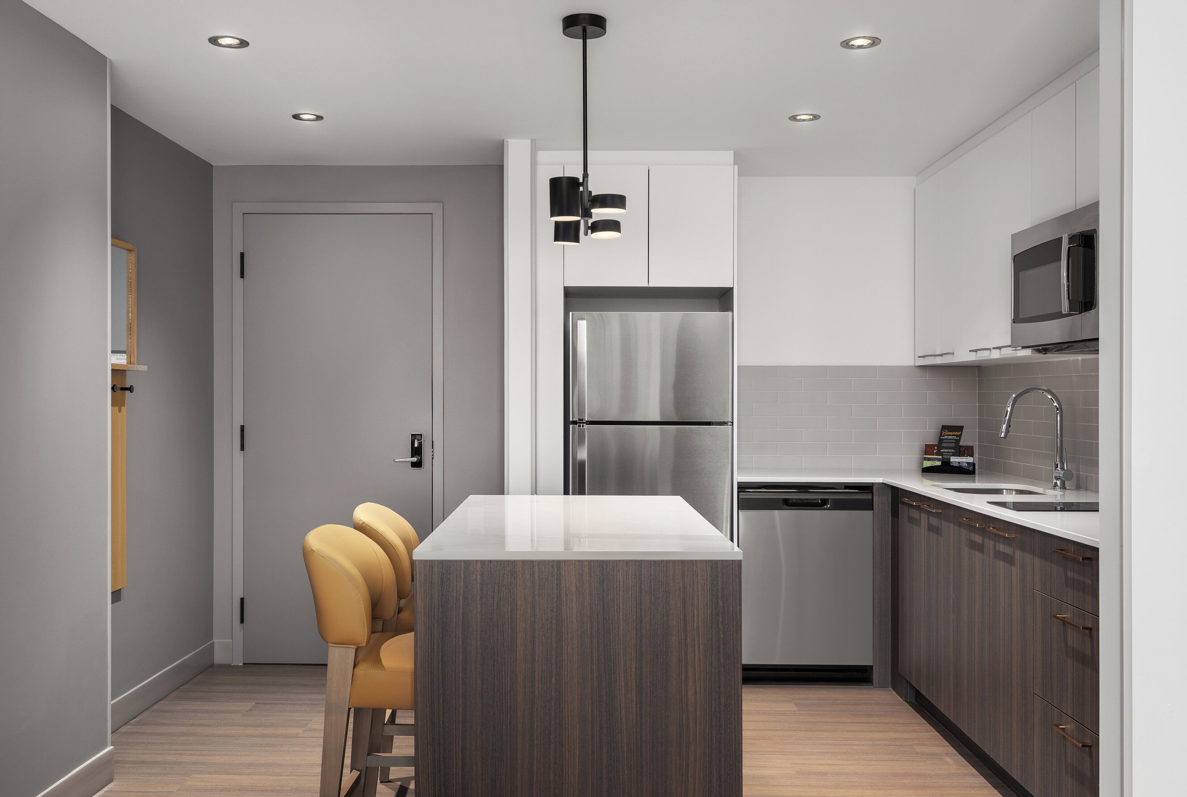 Uma cozinha moderna com ilha central, eletrodomésticos de aço inoxidável e lava-louças embutida.