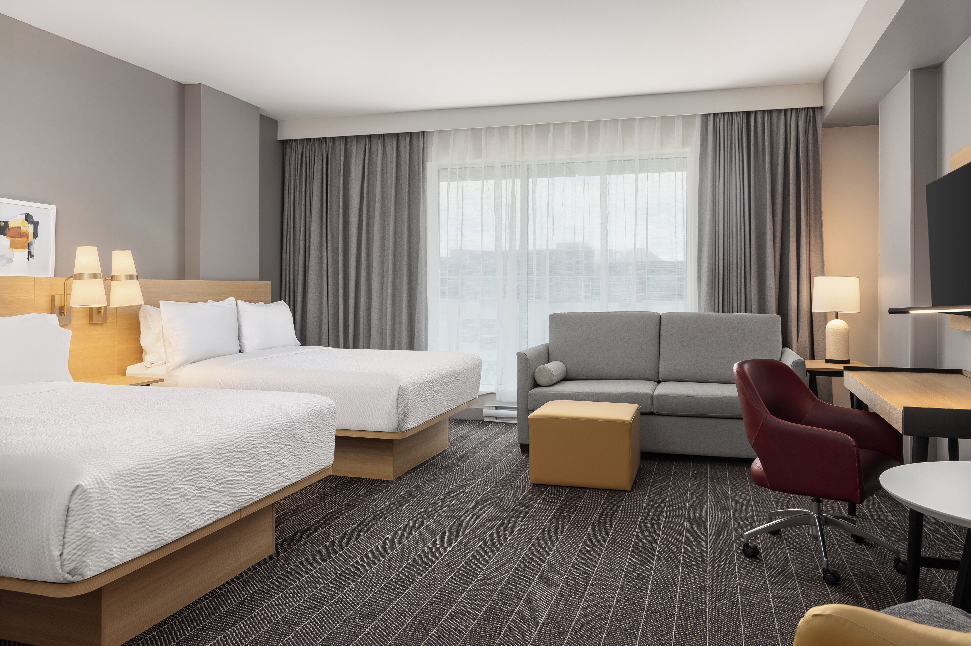 Habitación de hotel con dos camas, un sofá, un escritorio y una silla.