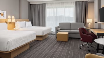 Habitación de hotel con dos camas, un sofá, un escritorio y una silla.
