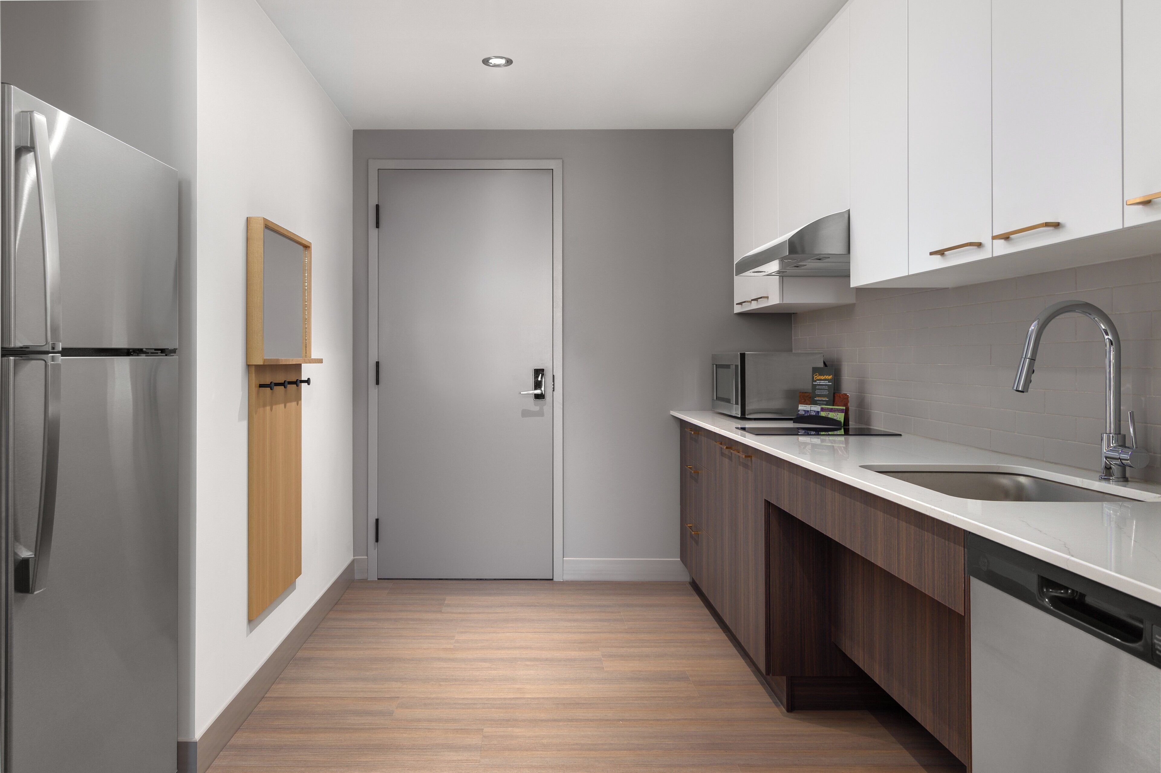 A modern kitchen with stainless steel appliances, a wooden door, and a built-in microwave.